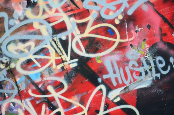Close-up fragment of a graffiti drawing applied to the wall by aerosol paint. The wall is spoiled by a multitude of colorful signatures and tags from street artists and hooligans
