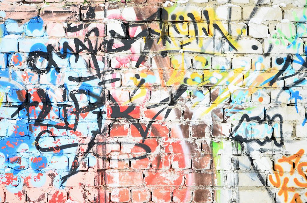 Close-up fragment of a graffiti drawing applied to the wall by aerosol paint. The wall is spoiled by a multitude of colorful signatures and tags from street artists and hooligans