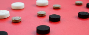 Beyaz, siyah ve kahverengi tablet bir sürü kırmızı yüzeyinde yalan. İlaç ve tıbbi konularda arka plan görüntüsü