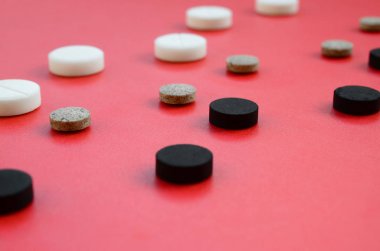 Beyaz, siyah ve kahverengi tablet bir sürü kırmızı yüzeyinde yalan. İlaç ve tıbbi konularda arka plan görüntüsü