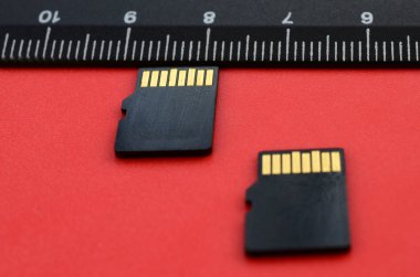 Siyah bir cetvel yanında kırmızı bir arka plan üzerinde iki küçük mikro Sd bellek kartları yalan. Küçük ve kompakt veri ve bilgi deposu