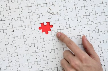 Beyaz jigsaw bulmaca monte durumunda kırmızı bir alan oluşturan bir eksik eleman ile doku erkek el parmak tarafından işaret