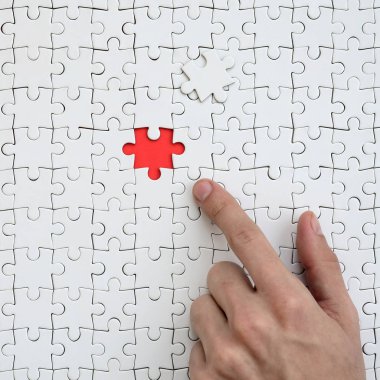 Beyaz jigsaw bulmaca monte durumunda kırmızı bir alan oluşturan bir eksik eleman ile doku erkek el parmak tarafından işaret