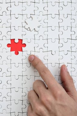 Beyaz jigsaw bulmaca monte durumunda kırmızı bir alan oluşturan bir eksik eleman ile doku erkek el parmak tarafından işaret