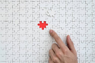 Beyaz jigsaw bulmaca monte durumunda kırmızı bir alan oluşturan bir eksik eleman ile doku erkek el parmak tarafından işaret