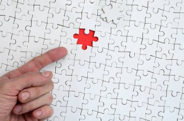 Beyaz jigsaw bulmaca monte durumunda kırmızı bir alan oluşturan bir eksik eleman ile doku erkek el parmak tarafından işaret