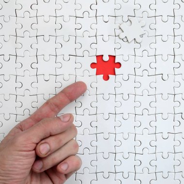 Beyaz jigsaw bulmaca monte durumunda kırmızı bir alan oluşturan bir eksik eleman ile doku erkek el parmak tarafından işaret