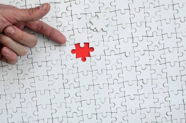 Beyaz jigsaw bulmaca monte durumunda kırmızı bir alan oluşturan bir eksik eleman ile doku erkek el parmak tarafından işaret