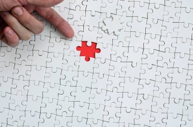 Beyaz jigsaw bulmaca monte durumunda kırmızı bir alan oluşturan bir eksik eleman ile doku erkek el parmak tarafından işaret