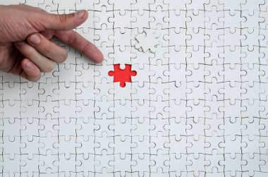 Beyaz jigsaw bulmaca monte durumunda kırmızı bir alan oluşturan bir eksik eleman ile doku erkek el parmak tarafından işaret
