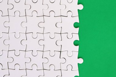Yeşil bir plastik yüzey zemin üzerine katlanmış beyaz jigsaw bulmaca parçası. Metin kopyalama yeri olan doku fotoğraf