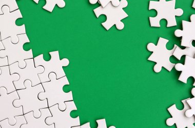 Katlanmış bir beyaz jigsaw puzzle ve bir yığın uncombed bulmaca öğeleri arka planı yeşil yüzey parçası. Metin için yer ile doku fotoğraf