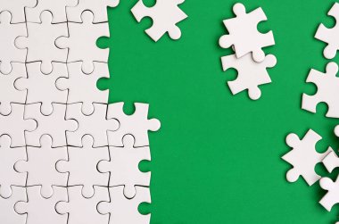 Katlanmış bir beyaz jigsaw puzzle ve bir yığın uncombed bulmaca öğeleri arka planı yeşil yüzey parçası. Metin için yer ile doku fotoğraf