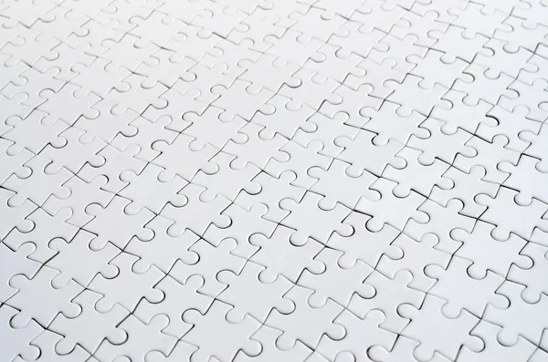 Close up of a white jigsaw puzzle in assembled state in perspective. Many components of a large whole mosaic are united