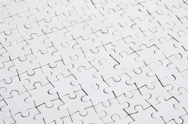 Close up of a white jigsaw puzzle in assembled state in perspective. Many components of a large whole mosaic are united