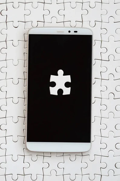 組み立てられた状態で白いジグソー パズルにタッチ画面でいくつかのパズル要素と近代的な大きなスマート フォン — ストック写真