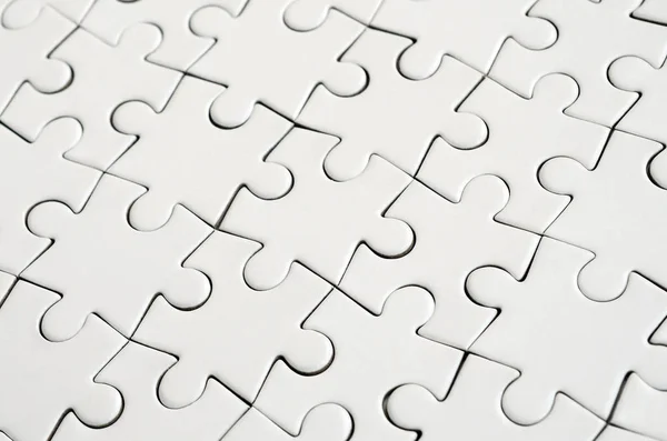 Close up of a white jigsaw puzzle in assembled state in perspective. Many components of a large whole mosaic are united