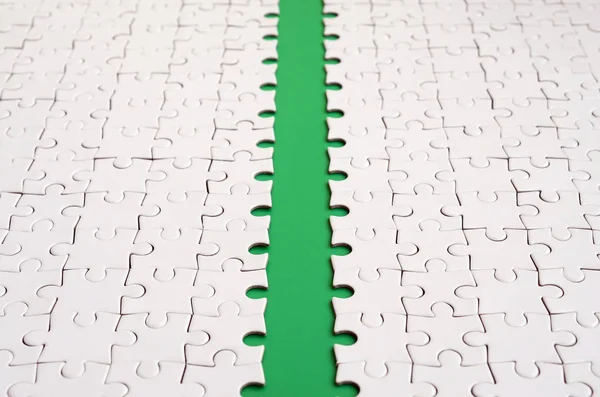 The green path is laid on the platform of a white folded jigsaw puzzle. Texture image with copy space for text