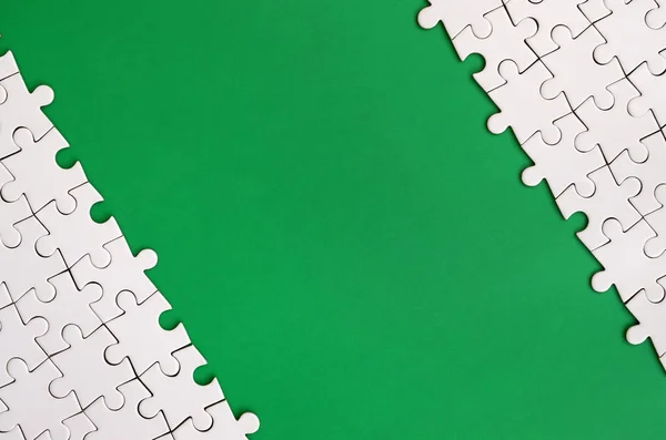 緑色のプラスチック表面の背景に折り畳まれた白いジグソー パズルの断片 コピーのテキストのための領域とテクスチャ写真 — ストック写真