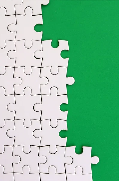 Фрагмент Сложенной Белой Головоломки Фоне Зеленой Пластиковой Поверхности Текстурная Фотография — стоковое фото