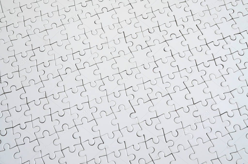 Close up texture of a white jigsaw puzzle in assembled condition. Top view. Many components of a large whole mosaic are united