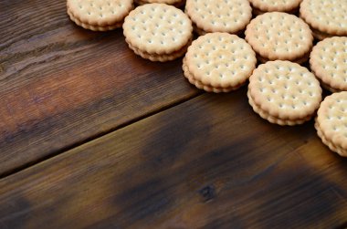 Yuvarlak sandviç kurabiye doldurma Hindistan cevizi ile büyük miktarlarda bir kahverengi ahşap yüzey üzerinde yer almaktadır. Kopya alanı ahşap bir zemin üzerine yemeklik fotoğrafı davranır