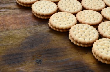 Yuvarlak sandviç kurabiye doldurma Hindistan cevizi ile büyük miktarlarda bir kahverengi ahşap yüzey üzerinde yer almaktadır. Kopya alanı ahşap bir zemin üzerine yemeklik fotoğrafı davranır