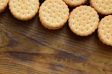 Yuvarlak sandviç kurabiye doldurma Hindistan cevizi ile büyük miktarlarda bir kahverengi ahşap yüzey üzerinde yer almaktadır. Kopya alanı ahşap bir zemin üzerine yemeklik fotoğrafı davranır