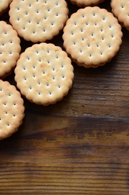 Yuvarlak sandviç kurabiye doldurma Hindistan cevizi ile büyük miktarlarda bir kahverengi ahşap yüzey üzerinde yer almaktadır. Kopya alanı ahşap bir zemin üzerine yemeklik fotoğrafı davranır