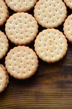 Yuvarlak sandviç kurabiye doldurma Hindistan cevizi ile büyük miktarlarda bir kahverengi ahşap yüzey üzerinde yer almaktadır. Kopya alanı ahşap bir zemin üzerine yemeklik fotoğrafı davranır