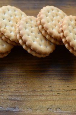 Yuvarlak sandviç kurabiye doldurma Hindistan cevizi ile büyük miktarlarda bir kahverengi ahşap yüzey üzerinde yer almaktadır. Kopya alanı ahşap bir zemin üzerine yemeklik fotoğrafı davranır