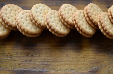 Yuvarlak sandviç kurabiye doldurma Hindistan cevizi ile büyük miktarlarda bir kahverengi ahşap yüzey üzerinde yer almaktadır. Kopya alanı ahşap bir zemin üzerine yemeklik fotoğrafı davranır