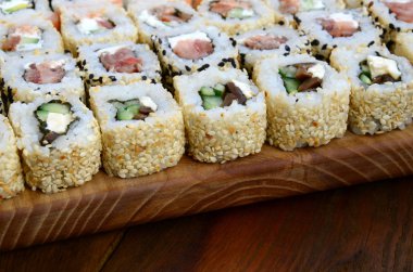 Bir sürü suşi Close-Up farklı dolguları yalanla ahşap yüzeyde alır. Bir kopya alanı ile pişmiş klasik Japon gıda makro çekim