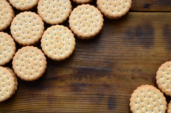 Yuvarlak sandviç kurabiye doldurma Hindistan cevizi ile büyük miktarlarda bir kahverengi ahşap yüzey üzerinde yer almaktadır. Kopya alanı ahşap bir zemin üzerine yemeklik fotoğrafı davranır