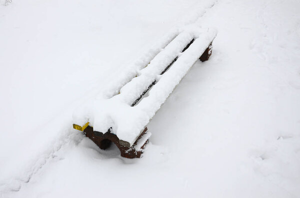 The bench, covered by a thick layer of a wall, is located on a snow-covered platform