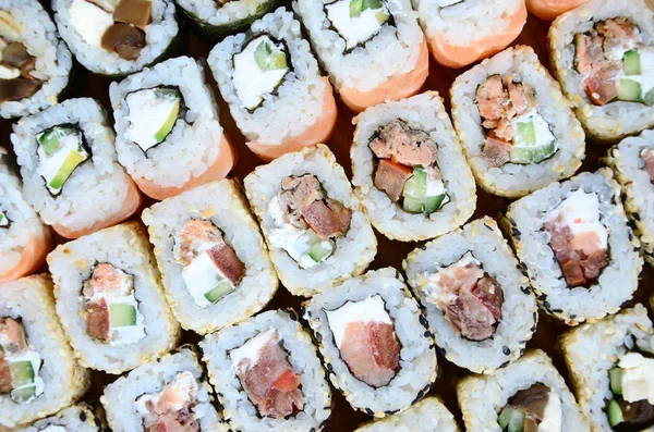 Close-up of a lot of sushi rolls with different fillings. Macro shot of cooked classic Japanese food. Background image