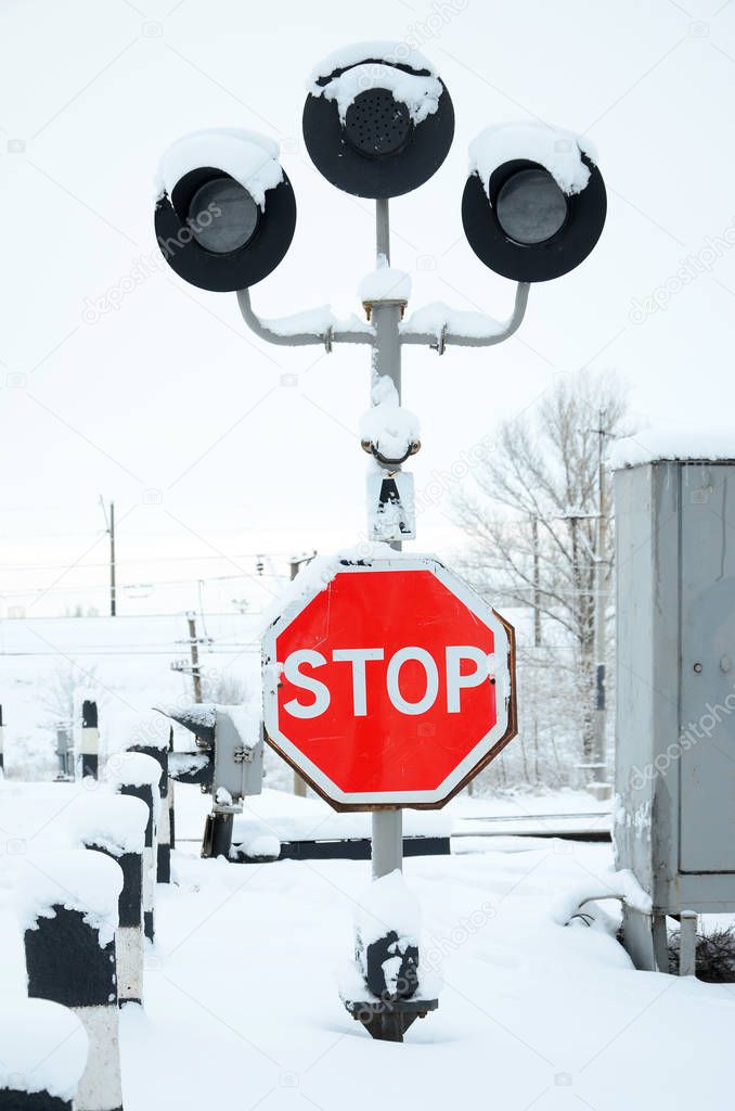 Stop. Red road sign is located on the motorway crossing the railway line in winter season