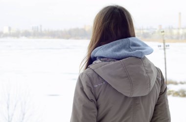 Kışın ufuk hattı Kuzey gökyüzü ve donmuş göl mesafe içine bakarak bir kahverengi ceket genç bir beyaz kız