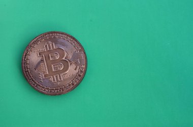 Fiziksel bitcoin şeklinde çikolata ürün yeşil bir plastik arka plan üzerinde yatıyor. Yenilebilir formdaki Kripto biriminin modeli