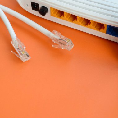 Internet yönlendirici ve Internet kablosu fiş bir parlak turuncu arka plan üzerinde yalan. Internet bağlantısı için gerekli öğeler
