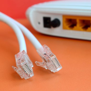 Internet yönlendirici ve Internet kablosu fiş bir parlak turuncu arka plan üzerinde yalan. Internet bağlantısı için gerekli öğeler