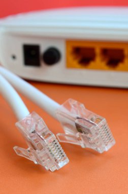 Internet yönlendirici ve Internet kablosu fiş bir parlak turuncu arka plan üzerinde yalan. Internet bağlantısı için gerekli öğeler