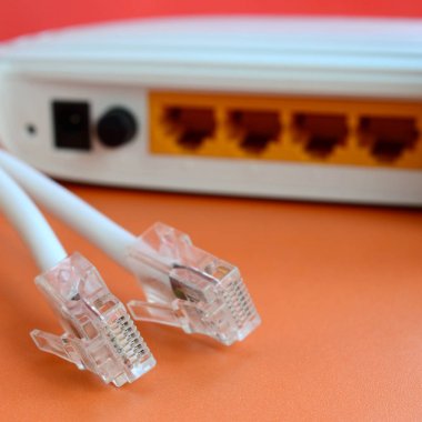 Internet yönlendirici ve Internet kablosu fiş bir parlak turuncu arka plan üzerinde yalan. Internet bağlantısı için gerekli öğeler