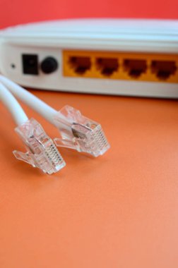 Internet yönlendirici ve Internet kablosu fiş bir parlak turuncu arka plan üzerinde yalan. Internet bağlantısı için gerekli öğeler