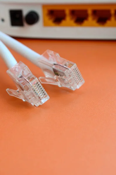 Roteador de Internet e plugues de cabo de Internet encontram-se em uma laranja brilhante — Fotografia de Stock