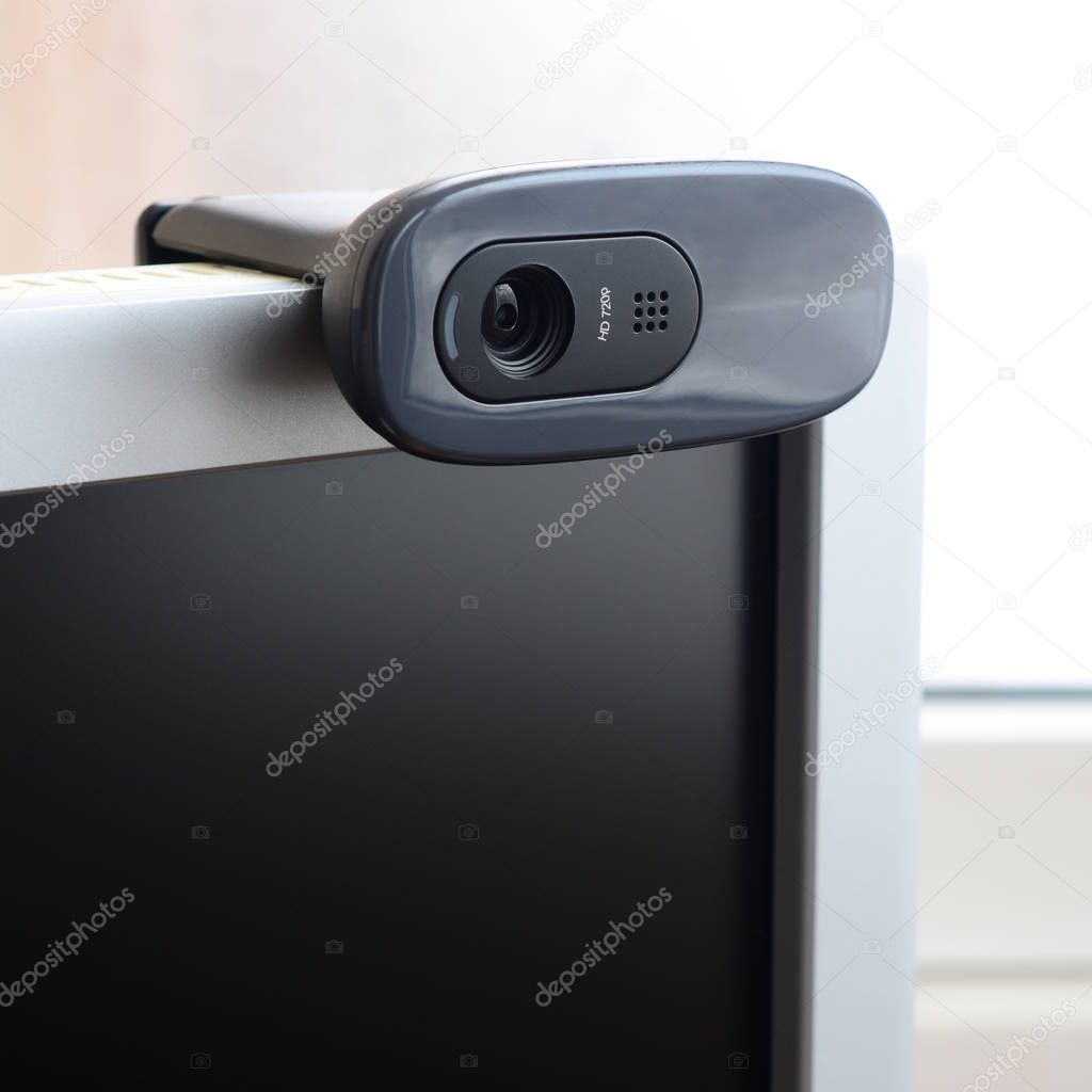 A modern web camera is installed on the body of a flat screen monitor. Device for video communication and recording of high quality video