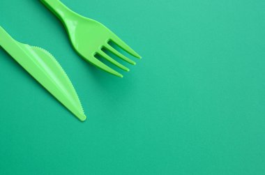Tek kullanımlık plastik çatal bıçak takımı yeşil. Plastik çatal ve bıçak bir yeşil arka yüzeyinde yalan