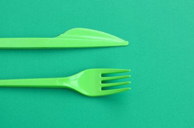 Tek kullanımlık plastik çatal bıçak takımı yeşil. Plastik çatal ve bıçak bir yeşil arka yüzeyinde yalan
