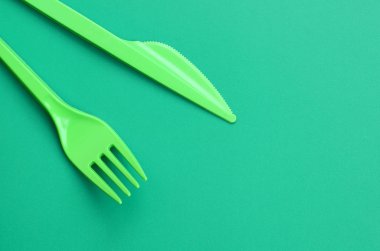 Tek kullanımlık plastik çatal bıçak takımı yeşil. Plastik çatal ve bıçak bir yeşil arka yüzeyinde yalan