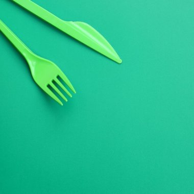 Tek kullanımlık plastik çatal bıçak takımı yeşil. Plastik çatal ve bıçak bir yeşil arka yüzeyinde yalan